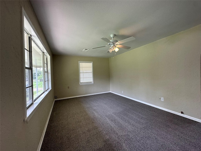 empty room featuring dark colored carpet and ceiling fan