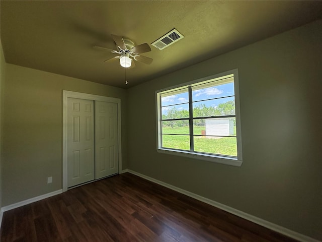 unfurnished bedroom with a closet, dark hardwood / wood-style floors, and ceiling fan