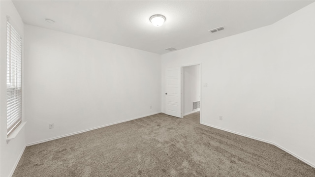 carpeted empty room featuring visible vents and baseboards