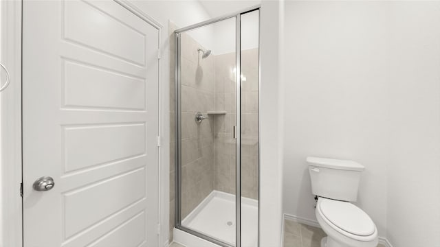 full bath featuring a stall shower, tile patterned flooring, toilet, and baseboards