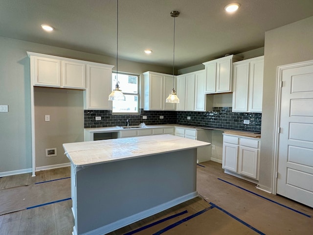 kitchen featuring a kitchen island, white cabinetry, light countertops, decorative backsplash, and decorative light fixtures