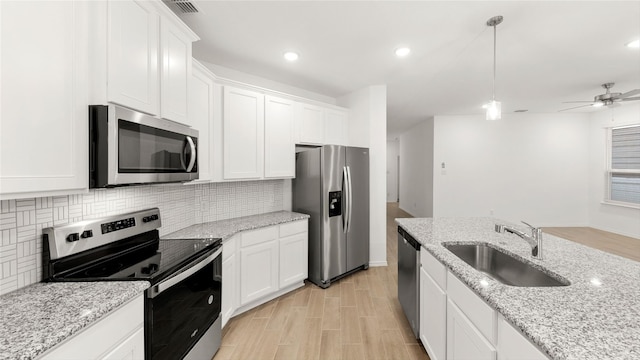 kitchen featuring sink, white cabinets, pendant lighting, and appliances with stainless steel finishes