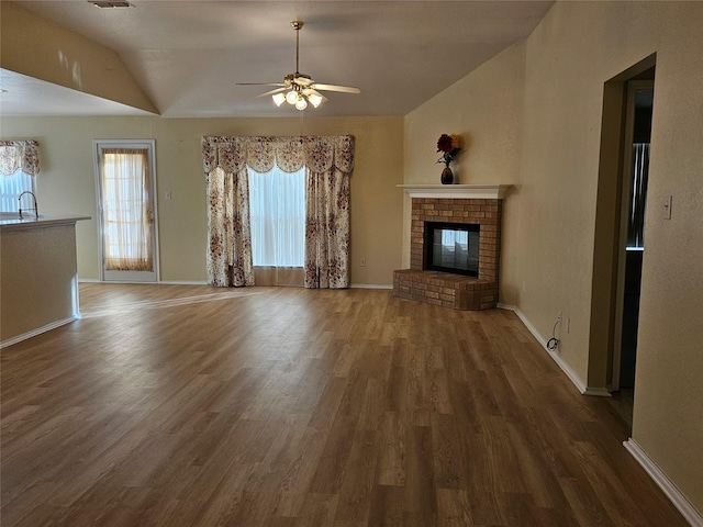 unfurnished living room with dark wood-type flooring, lofted ceiling, sink, ceiling fan, and a fireplace