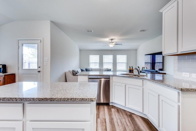 kitchen featuring backsplash, stainless steel dishwasher, sink, white cabinets, and a center island