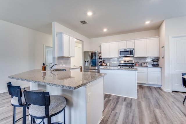 kitchen featuring white cabinets, stainless steel appliances, kitchen peninsula, and sink