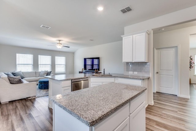 kitchen featuring a center island, white cabinets, stainless steel dishwasher, ceiling fan, and tasteful backsplash