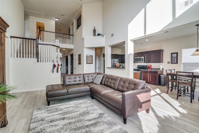 living room featuring light hardwood / wood-style floors and a high ceiling