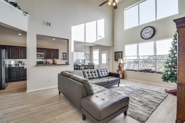 living room featuring sink, ceiling fan, and light wood-type flooring