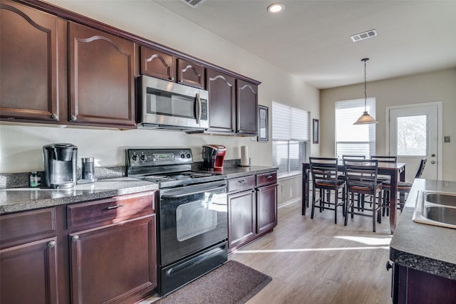 kitchen with black / electric stove, decorative light fixtures, light hardwood / wood-style floors, and a healthy amount of sunlight