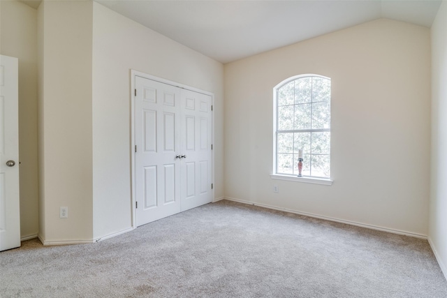 unfurnished bedroom with a closet, lofted ceiling, and light carpet