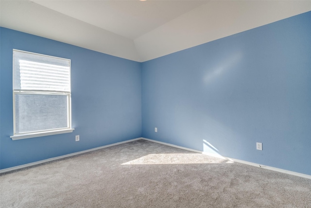 spare room featuring lofted ceiling and light colored carpet