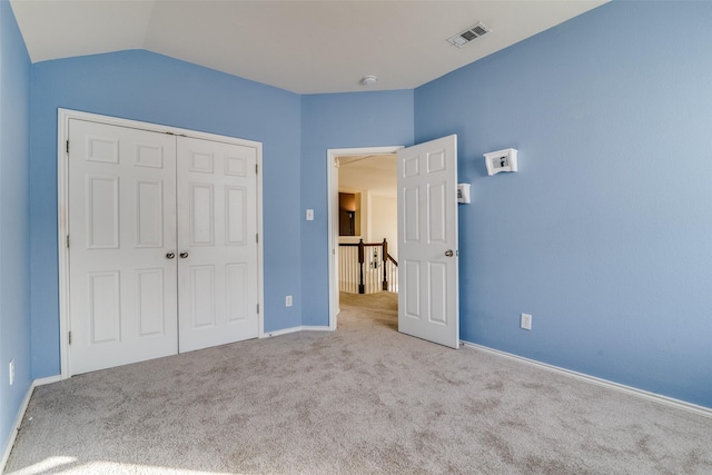 unfurnished bedroom with light carpet, lofted ceiling, and a closet