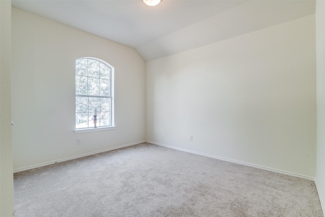 carpeted spare room with vaulted ceiling