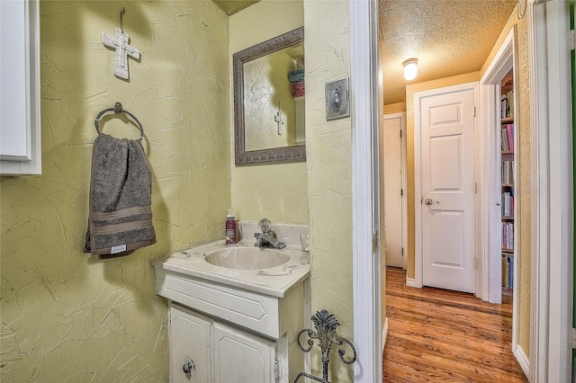 bathroom with hardwood / wood-style floors, vanity, and a textured ceiling