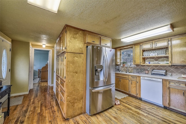 kitchen featuring tasteful backsplash, a textured ceiling, white dishwasher, hardwood / wood-style floors, and stainless steel fridge with ice dispenser