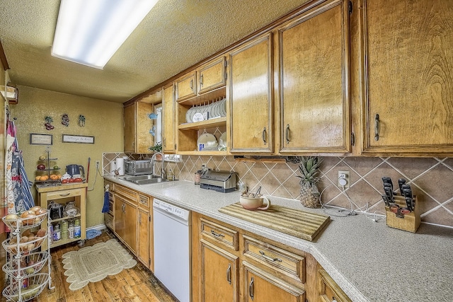 kitchen with hardwood / wood-style floors, dishwasher, sink, a textured ceiling, and tasteful backsplash