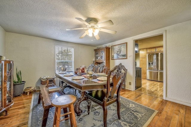 dining area with ceiling fan, light hardwood / wood-style flooring, and a textured ceiling