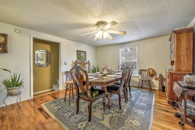 dining room with ceiling fan, light hardwood / wood-style flooring, and a textured ceiling