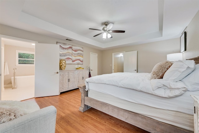 bedroom featuring light hardwood / wood-style flooring, a raised ceiling, and ceiling fan