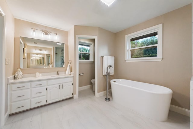 bathroom featuring a bath, vanity, a healthy amount of sunlight, and toilet