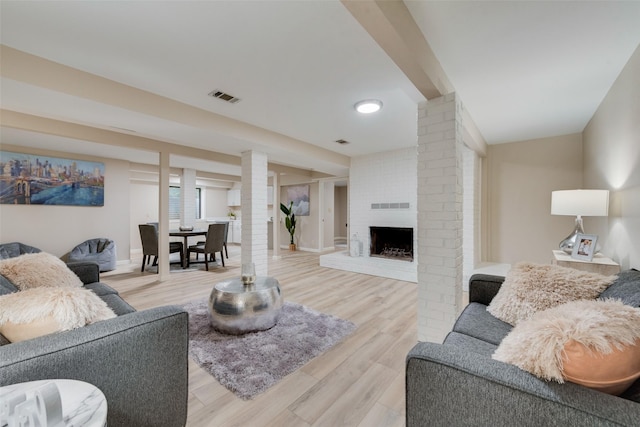 living room featuring light hardwood / wood-style flooring and a brick fireplace