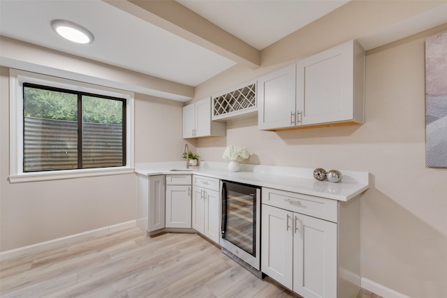 kitchen with white cabinetry, beverage cooler, and light hardwood / wood-style flooring