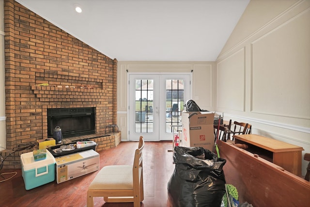 living room featuring hardwood / wood-style floors, vaulted ceiling, a fireplace, and french doors