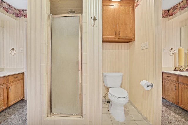 bathroom with tile patterned flooring, vanity, toilet, and walk in shower