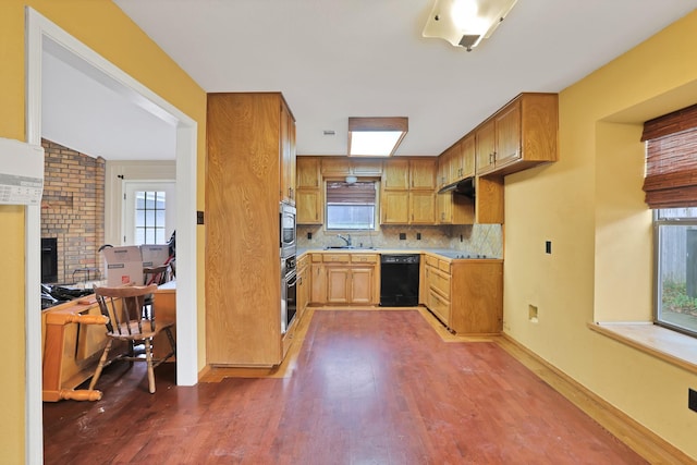 kitchen with dark wood-type flooring, sink, tasteful backsplash, a fireplace, and black appliances