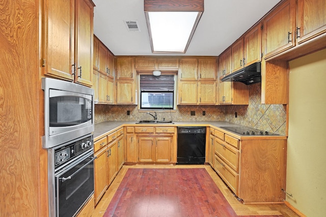 kitchen featuring dark wood-type flooring, sink, tasteful backsplash, and black appliances