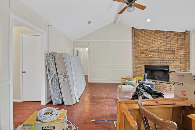 interior space with lofted ceiling with beams, ceiling fan, and a fireplace