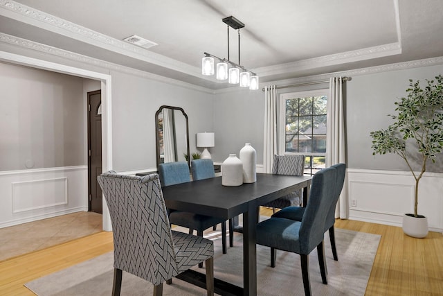 dining room featuring a raised ceiling and light hardwood / wood-style flooring