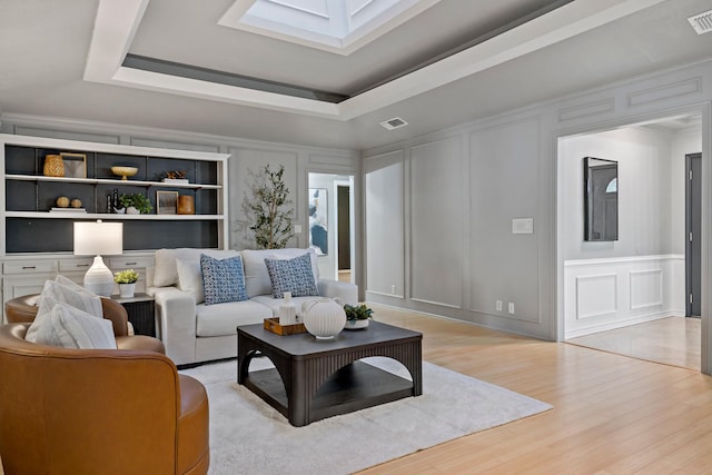 living room featuring a tray ceiling and light hardwood / wood-style flooring