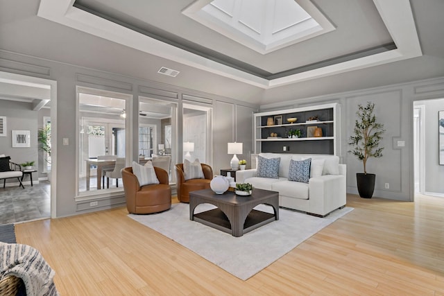 living room featuring light wood-type flooring and a tray ceiling