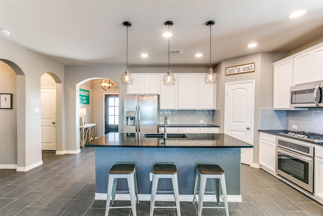 kitchen with white cabinets, sink, an island with sink, and stainless steel appliances