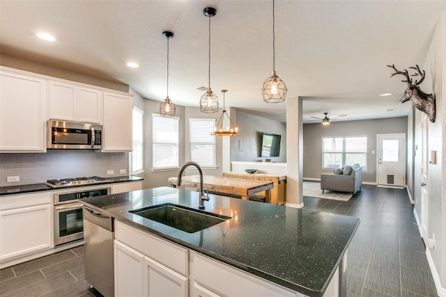 kitchen featuring white cabinets, sink, appliances with stainless steel finishes, and an island with sink