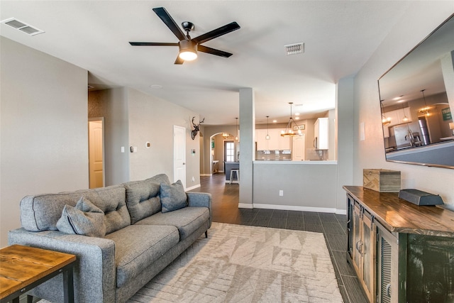 living room with ceiling fan with notable chandelier and dark wood-type flooring