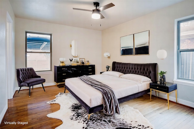 bedroom with ceiling fan, wood-type flooring, and multiple windows