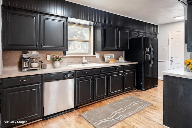 kitchen with black fridge, light hardwood / wood-style flooring, stainless steel dishwasher, and sink