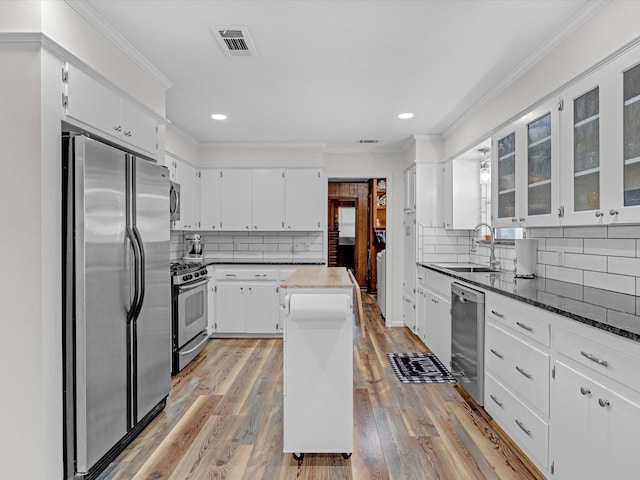 kitchen featuring a kitchen island, appliances with stainless steel finishes, sink, white cabinets, and crown molding