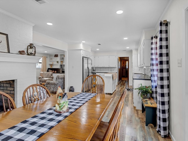 dining space featuring crown molding, a fireplace, and light wood-type flooring