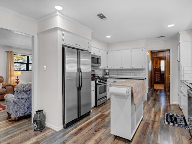 kitchen with white cabinetry, crown molding, tasteful backsplash, appliances with stainless steel finishes, and hardwood / wood-style flooring