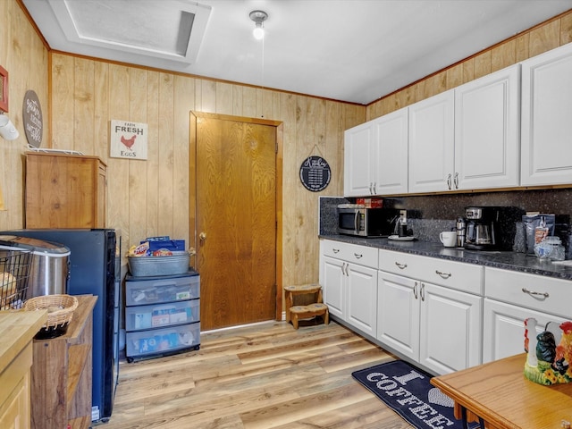 kitchen with white cabinetry, wooden walls, and light hardwood / wood-style floors