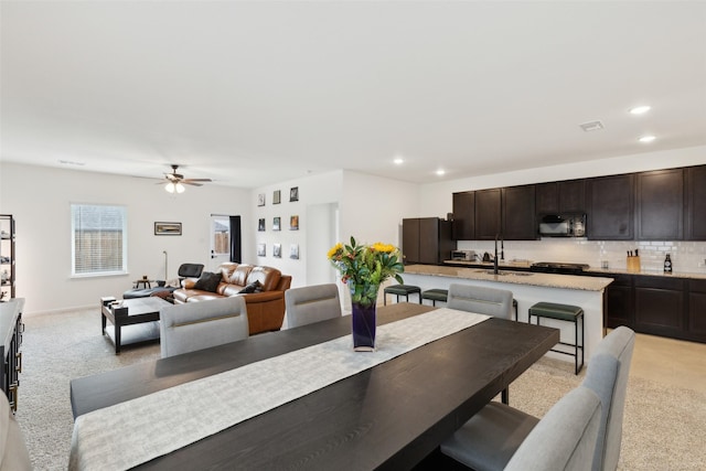 carpeted dining area with ceiling fan and sink