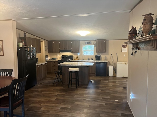 kitchen featuring black appliances, dark hardwood / wood-style floors, a kitchen island, a kitchen bar, and dark brown cabinetry