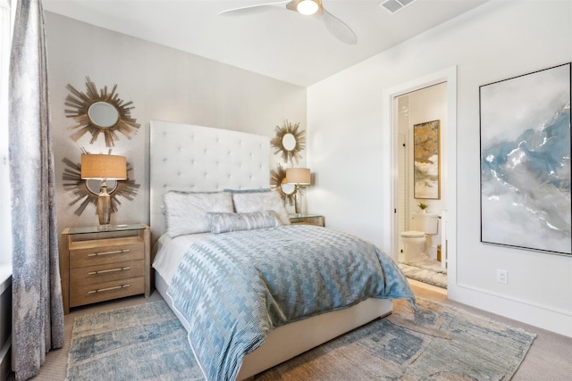 carpeted bedroom with ensuite bathroom and ceiling fan