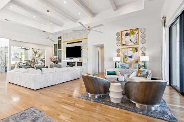 living room featuring ceiling fan, beam ceiling, hardwood / wood-style floors, and a towering ceiling