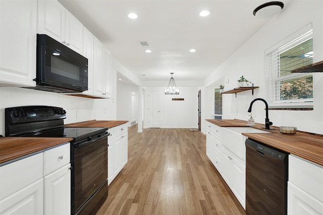 kitchen featuring wooden counters, black appliances, pendant lighting, light hardwood / wood-style flooring, and white cabinets