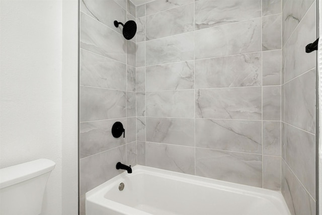 bathroom featuring toilet and tiled shower / bath