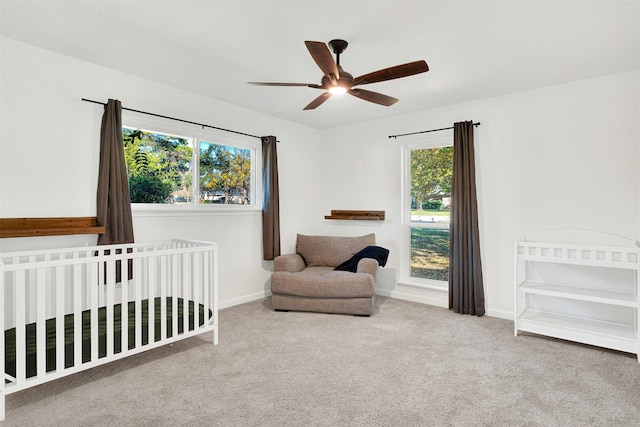 bedroom with carpet, ceiling fan, multiple windows, and a nursery area